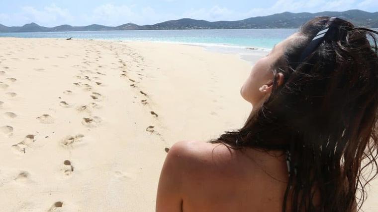 Footprints in the white sand of a Buck Island beach beside turquoise water