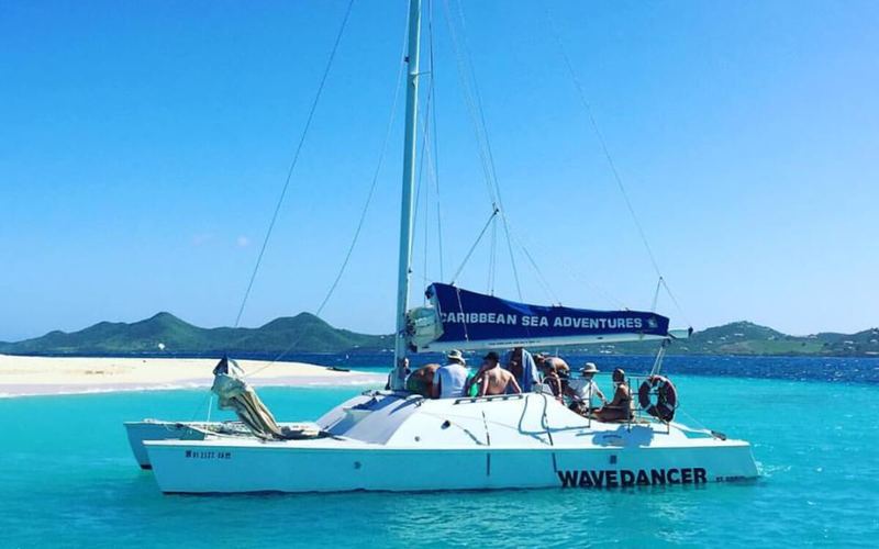 Wave Dancer catamaran with guests aboard off a Buck Island beach
