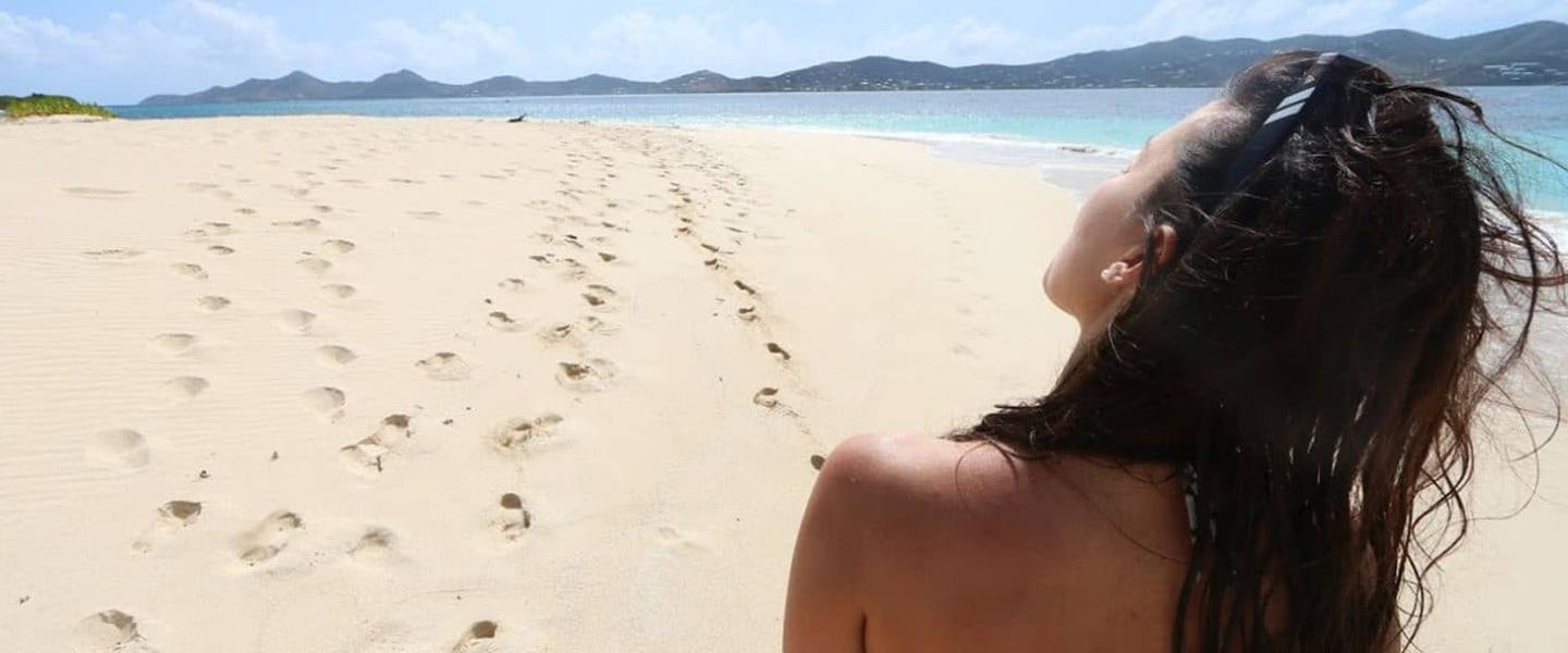 A guest relaxing on the white sand beach at Buck Island, St. Croix