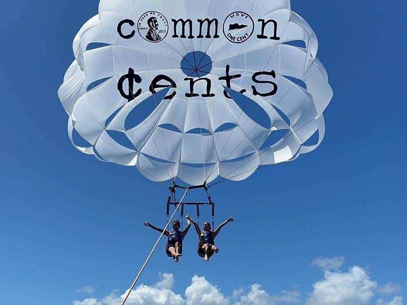 Two parasailers under a white parachute over the Caribbean off St. Croix