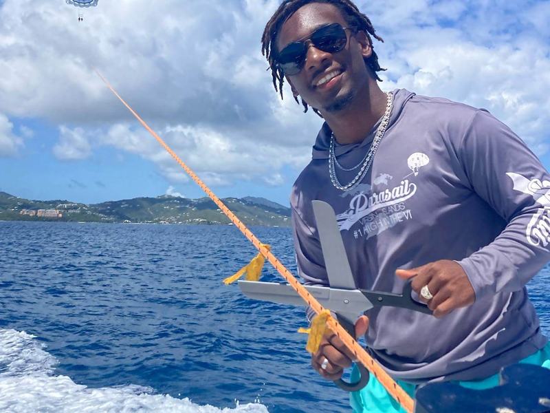 A smiling parasail crew member holding the tow line on the boat