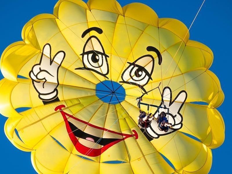 A yellow smiley face parachute against a blue sky
