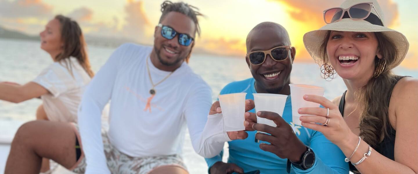 Friends toasting with drinks at sunset aboard Celebration on a private sunset cruise