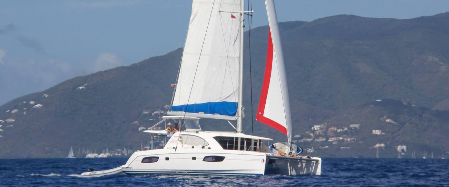 The Inconceivable sailing catamaran under sail off the green hills of St. Croix