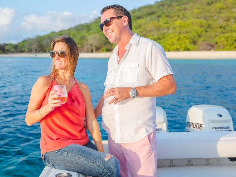 A couple with drinks aboard Smooth Recovery off a green St. Croix shoreline