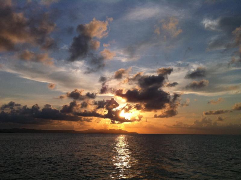 The sun setting through dark clouds over the Caribbean