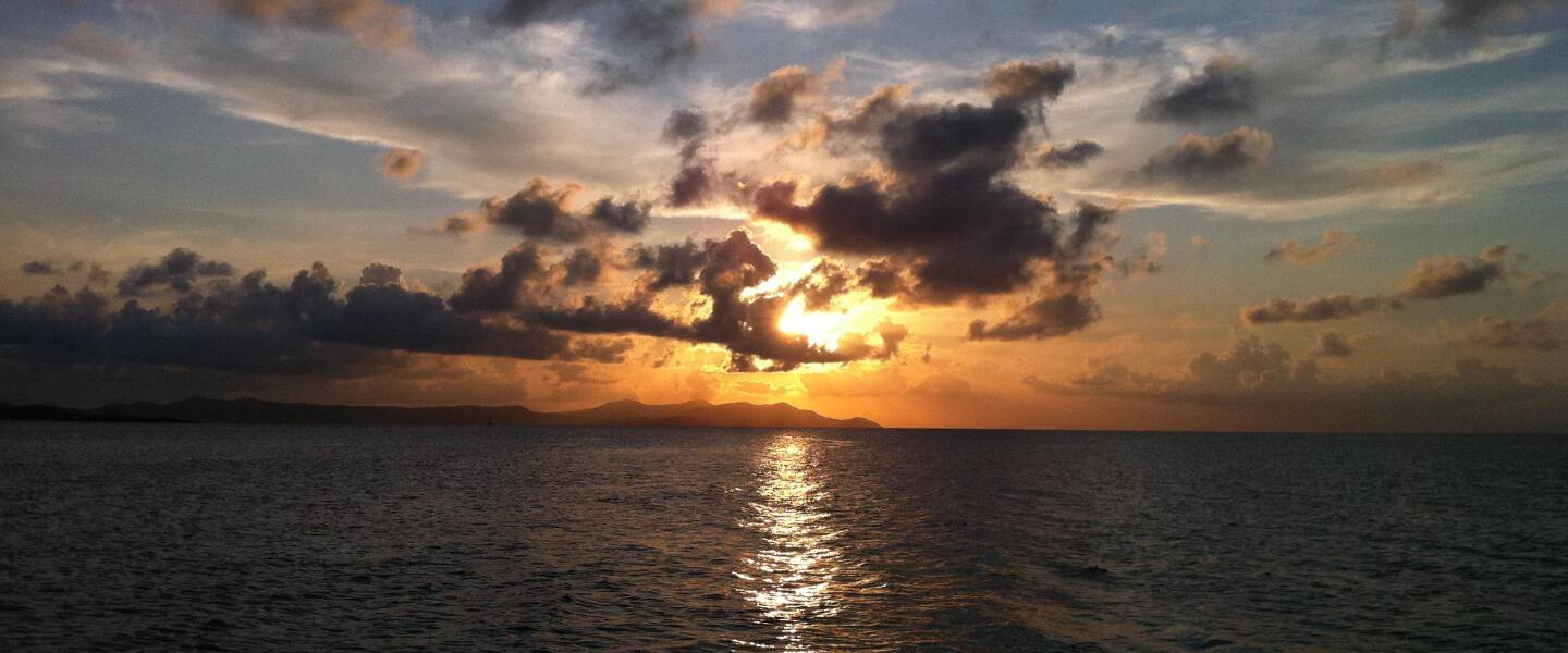 Pink and gold clouds over the Caribbean at sunset on a Smooth Recovery private sunset cruise