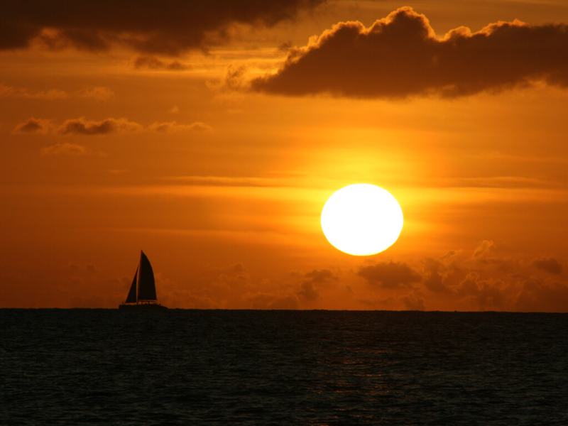 The sun setting over the Caribbean with a sailboat on the horizon off St. Croix