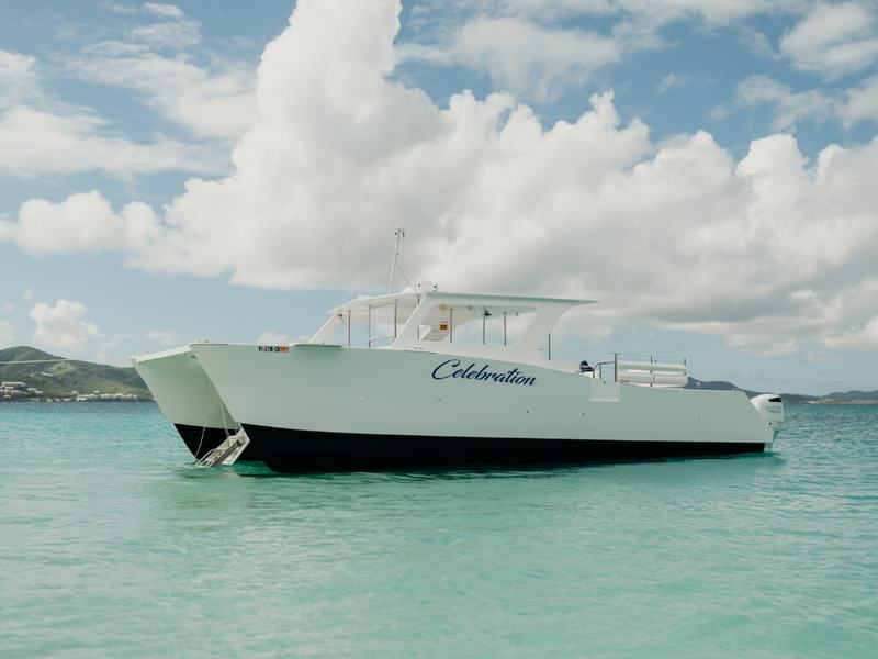 Celebration anchored in shallow turquoise water off a beach