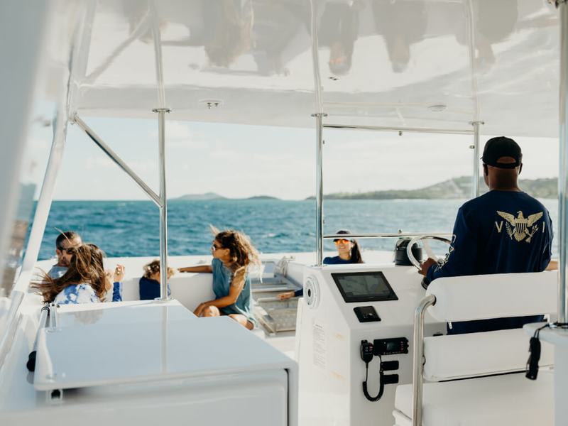 Guests under the shade of Celebration&rsquo;s upper deck with the captain at the helm
