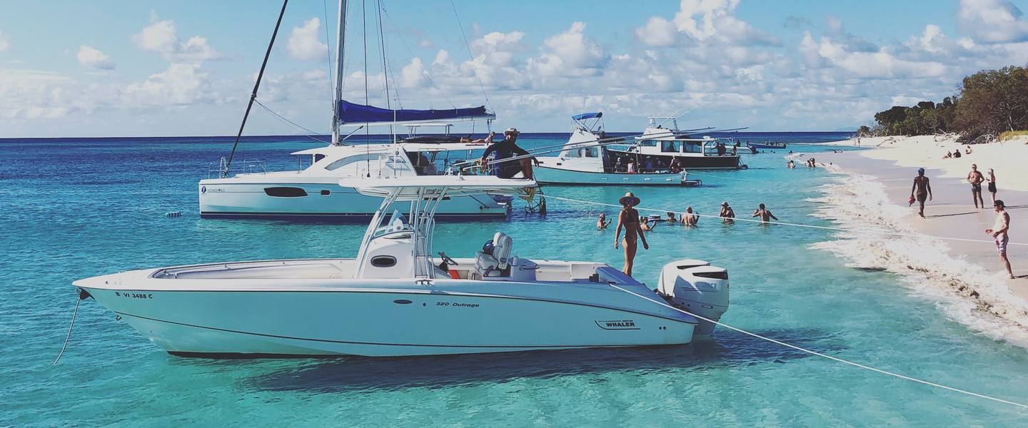 Caribbean Sea Adventures private charter boats anchored off a white-sand Buck Island beach