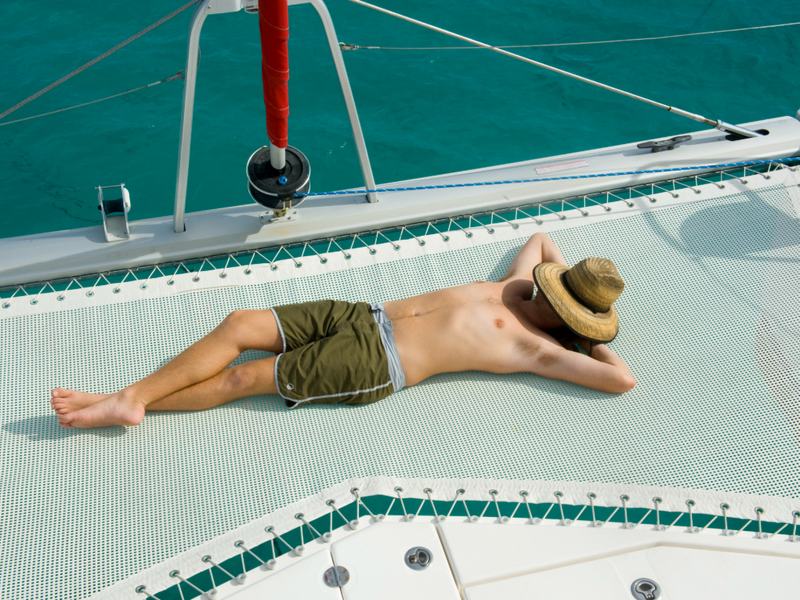 The trampoline netting at the bow of Inconceivable over turquoise water