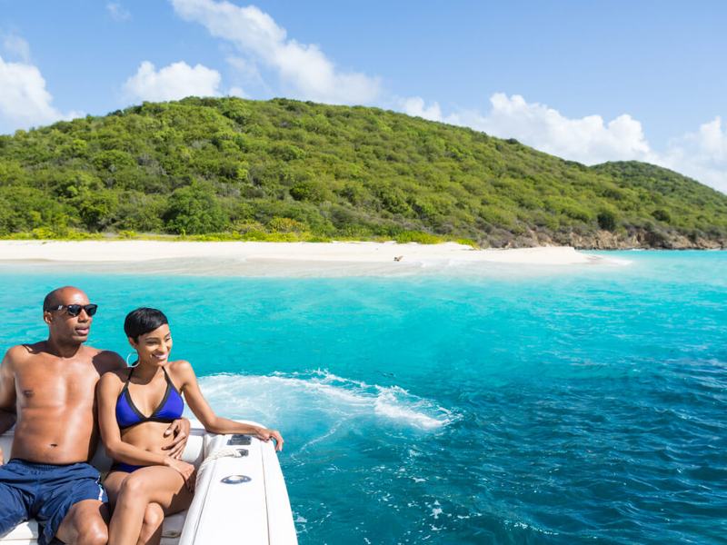 A couple aboard Smooth Recovery with the green hills of Buck Island behind
