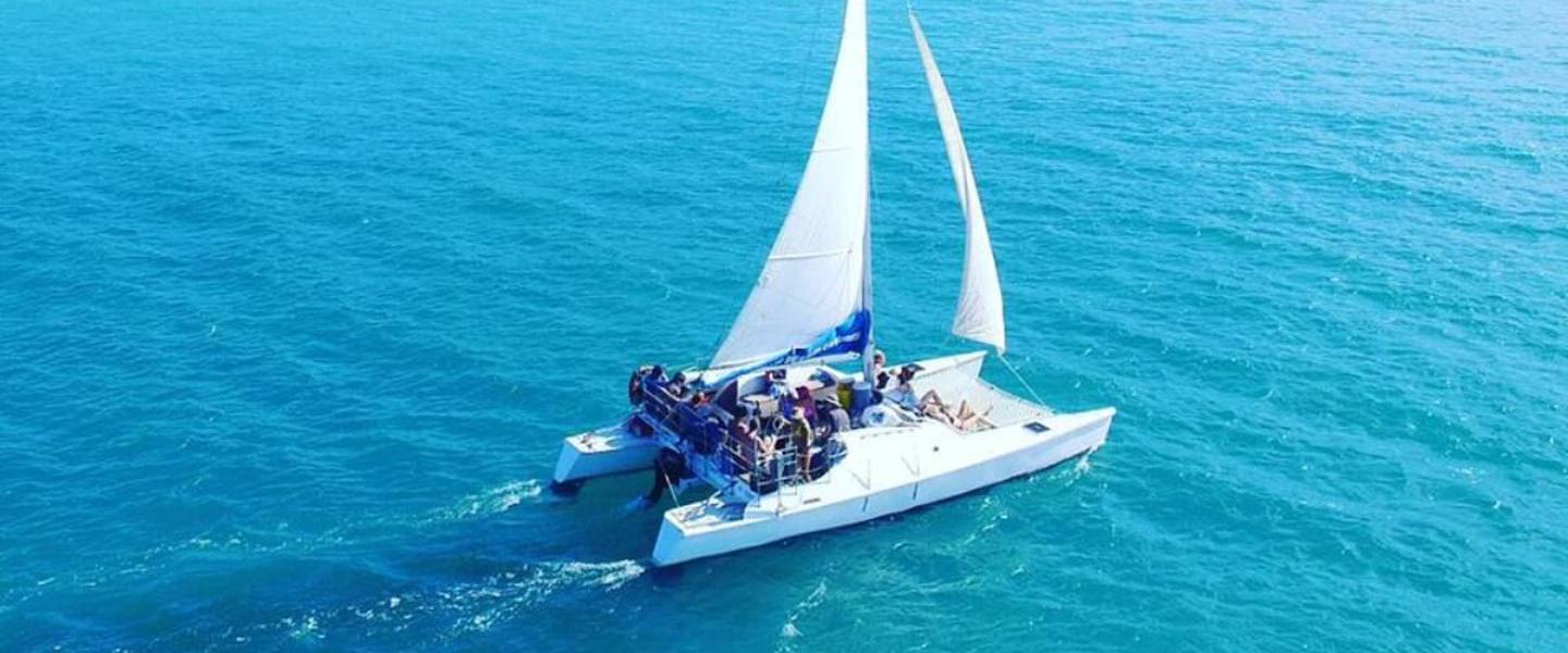 Aerial view of the Wave Dancer sailing catamaran under sail with guests aboard