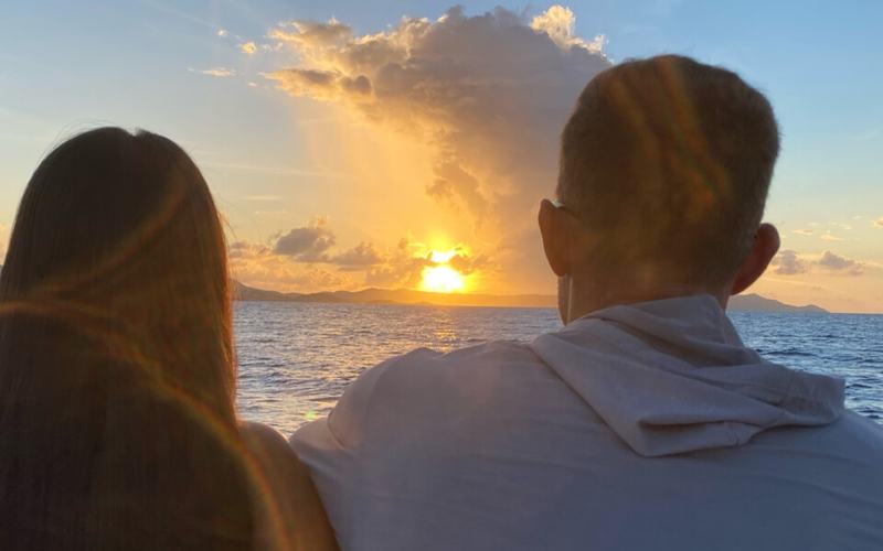 A couple watching the sun set from the bow of Celebration on the family friendly sunset cruise